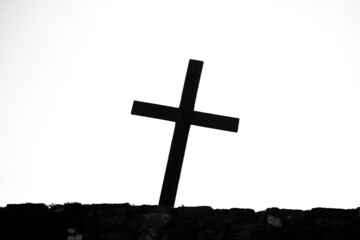 crooked catholic christian cross silhouette on cemetery fence. Black and white