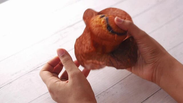rear view of women hand holding muffin cake on table 