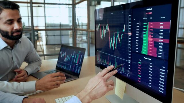 Two diverse crypto traders brokers stock exchange market investors discussing trading charts research reports growth using pc computer looking at screen analyzing invest strategy, financial profit.