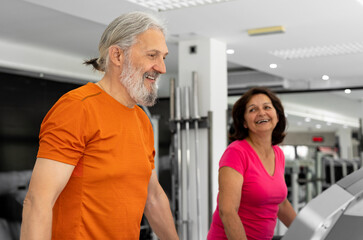 A beautiful elderly couple is working out together in the gym