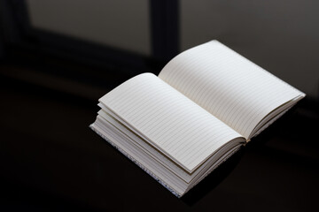 Opened blank notebook isolated on dark table background.