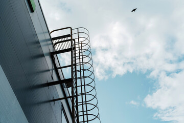 Emergency evacuation metal staircase on the facade of an industrial building. Bottom up view