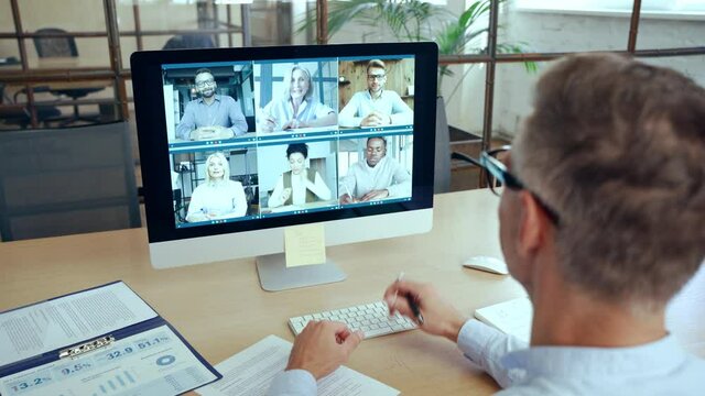 Corporate leader manager leading videoconference with diverse team business people having digital group video call conference working in office at online virtual meeting on pc computer. Over shoulder