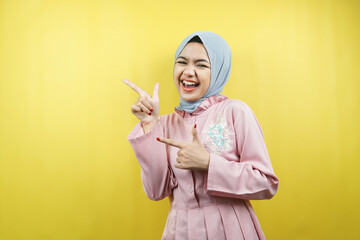 Cheerful beautiful young muslim woman, pointing to empty space, promoting something, isolated