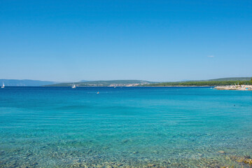 The late summer coastline near to Punat on Krk Island in Primorje-Gorski Kotar County in western Croatia. A cormorant can be seen on the rocks on the left
