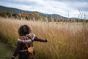 Foto op Plexiglas curly hair woman running hand through the tallgrass prairie © pelenguino