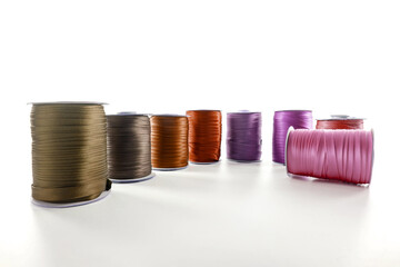 rolls with brown and red decorative ribbons of different shades for clothes on a white background