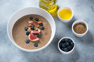 Bowl of flaxseed porridge over light-blue stone background, elevated view, horizontal shot