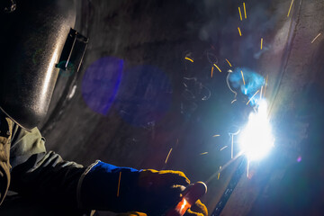 Fototapeta premium MMA welding. A welder welds large diameter pipes with manual electric arc welding.