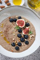 Close-up of flaxseed porridge served with blueberry, sliced figs and almonds, vertical shot, top view