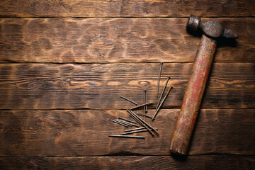 Old hammer and nails work tools on the wooden flat lay workbench background with copy space.