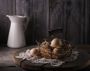 Still life with fresh chicken eggs in a wicker basket on a wooden table.