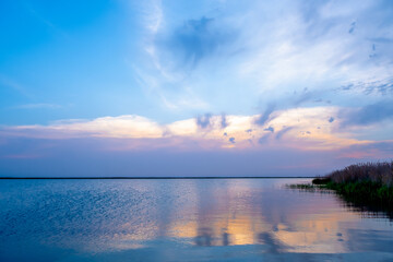 Naklejka premium Beautiful, colorful sunset sunrise over a lake. Crepuscular rays and clouds reflected in calm water.