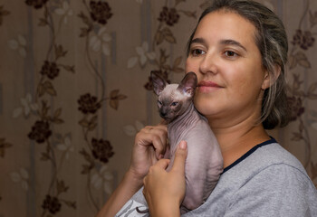 A beautiful girl is holding a young sphinx in her arms.