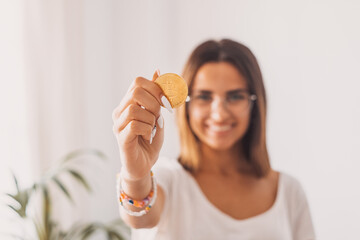 Teenager holding a virtual golden bitcoin with his hand showing it to the camera smiling and having fun.