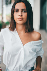 Happy young fashionable woman with short hair looking at camera outdoors. Beautiful satisfied lady with short hair smiling while facing camera. Portrait of confident female youth smiling.