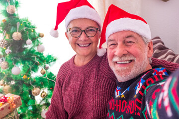 Couple of two old people smiling and looking at the camera - family selfie at home the christmas day together.