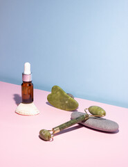 Cosmetic product in a glass bottle with a pipette and gua sha e scraper and roller. Smooth stones...