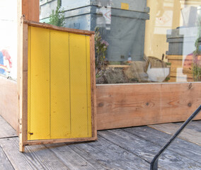 Honeycomb of bee with new wax leaning against an apiary. Beekeeping concept.