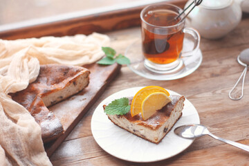 curd casserole with orange, lemon and mint leaf, tea in transparent cup