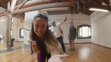 Tracking shot of young female teacher dancing in ballroom. Handheld shot of happy senior people hopping in circle, enjoying music and hanging out during dance class. Having fun, hobby concept - Powered by Adobe