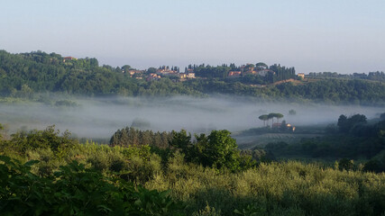A view of a misty Tuscan valley on a sunny holiday morning.