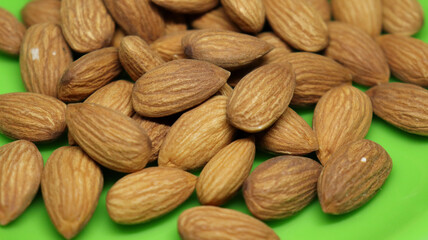 The pile of almonds is on a green plate