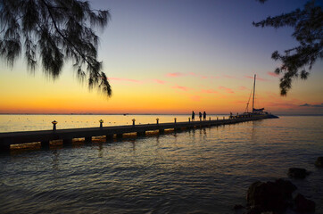 Fototapeta na wymiar Pier with people walking from a boat, at sunset, Rum Point, Grand Cayman
