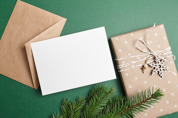 Christmas greeting card mockup with decorated gift box, envelope and green fir tree branch