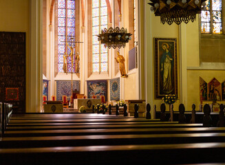 Ławki w kościele katolickim z widokiem na ołtarz. 