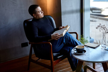 A young girl is sitting in a cafe reading a book. The concept of education and remote work