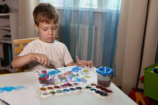 A boy draws with paints at a table in his room. High quality FullHD footageA boy draws with paints at a table in his room.