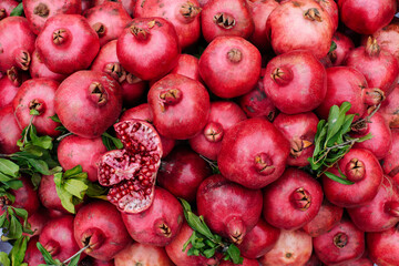Fototapeta na wymiar juicy and ripe pomegranates heaped in a tray at the farmers' market