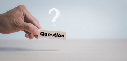Hand hold Wooden cube block in question mark mean what on cement table background, column of wooden...