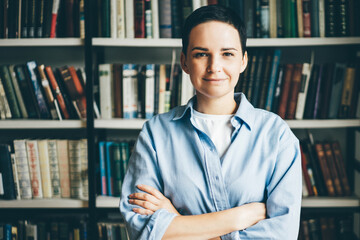 Young woman standing in front of bookshelves. Education concept.