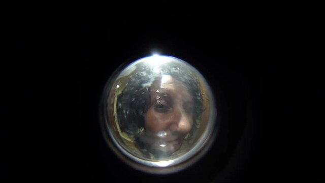 View of a woman standing in front of the door, view from the entrance door peephole