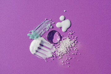 Cosmetic smears and drops. Appearance of the texture of the cream, oil and granules on a purple background. Natural skincare products. Beauty concept for face and body care