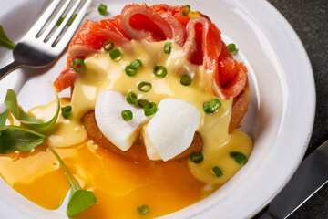 Eggs Benedict with salmon and hollandaise sauce on plate