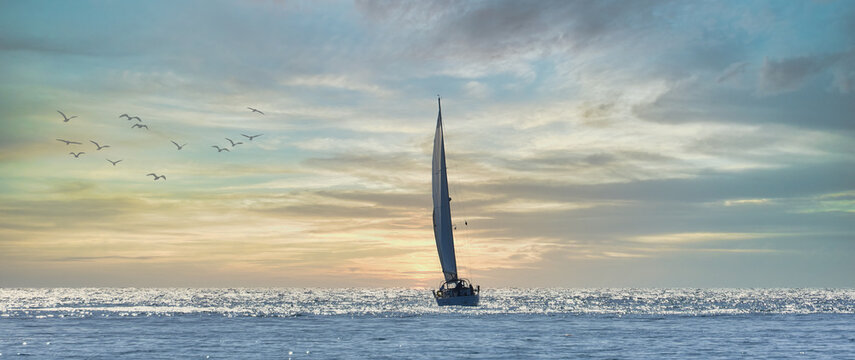 Sailboat sailing towards the horizon at sunset