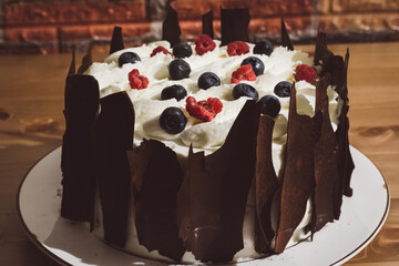 Black forest cake decorated with whipped cream, chocolate and berries. Schwartzwald cake