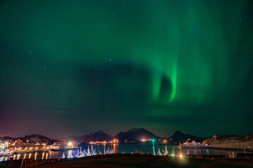 Un village de pêcheurs sous un ciel illuminé par une aurore boréale aux îles Lofoten en Norvège.