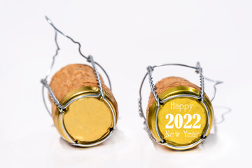 Fototapeta na wymiar Closeup of two champagne corks with their cage on white. One cork has the date 2022