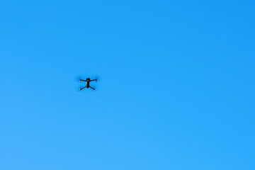 An unmanned quadcopter with a digital camera in the blue sky.