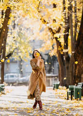 Young woman walking on an alley in a park on warm autumn day.