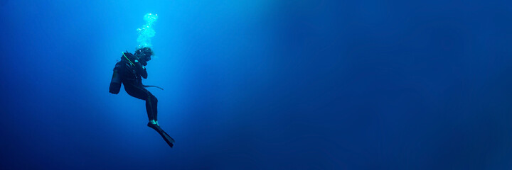 Background banner with a scuba diver woman standing still in deep blue 