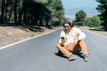 Young boy listening to music while sitting on his skateboard.