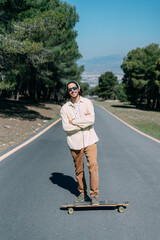 Portrait of young boy with sunglasses and a skateboard and crossed arms.