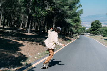 Hipster boy riding a skateboard with his arms outstretched in the street © Luis