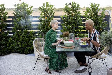 Multiracial couple eating organic food at dinner outdoors. Concept of relationship. Idea of healthy eating. Modern domestic lifestyle. Black man and european woman enjoying time together