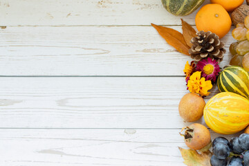 Top view of white wooden background with fall fruits (pumpkins, grapes, tangerines, medlars, flowers, and leaves). The concept of thanksgiving and thankfulness to God Jesus Christ. Copy space.
